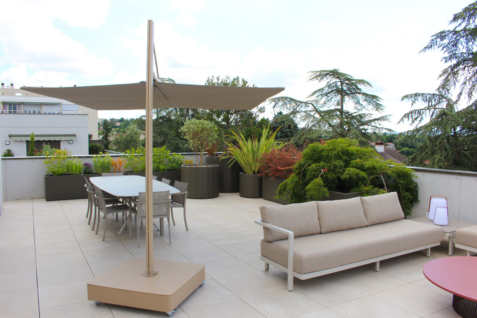 Terrasse de toit dallée avec canapé d'extérieur, parasol déporté et bacs alu laqués plantés – projet ACER