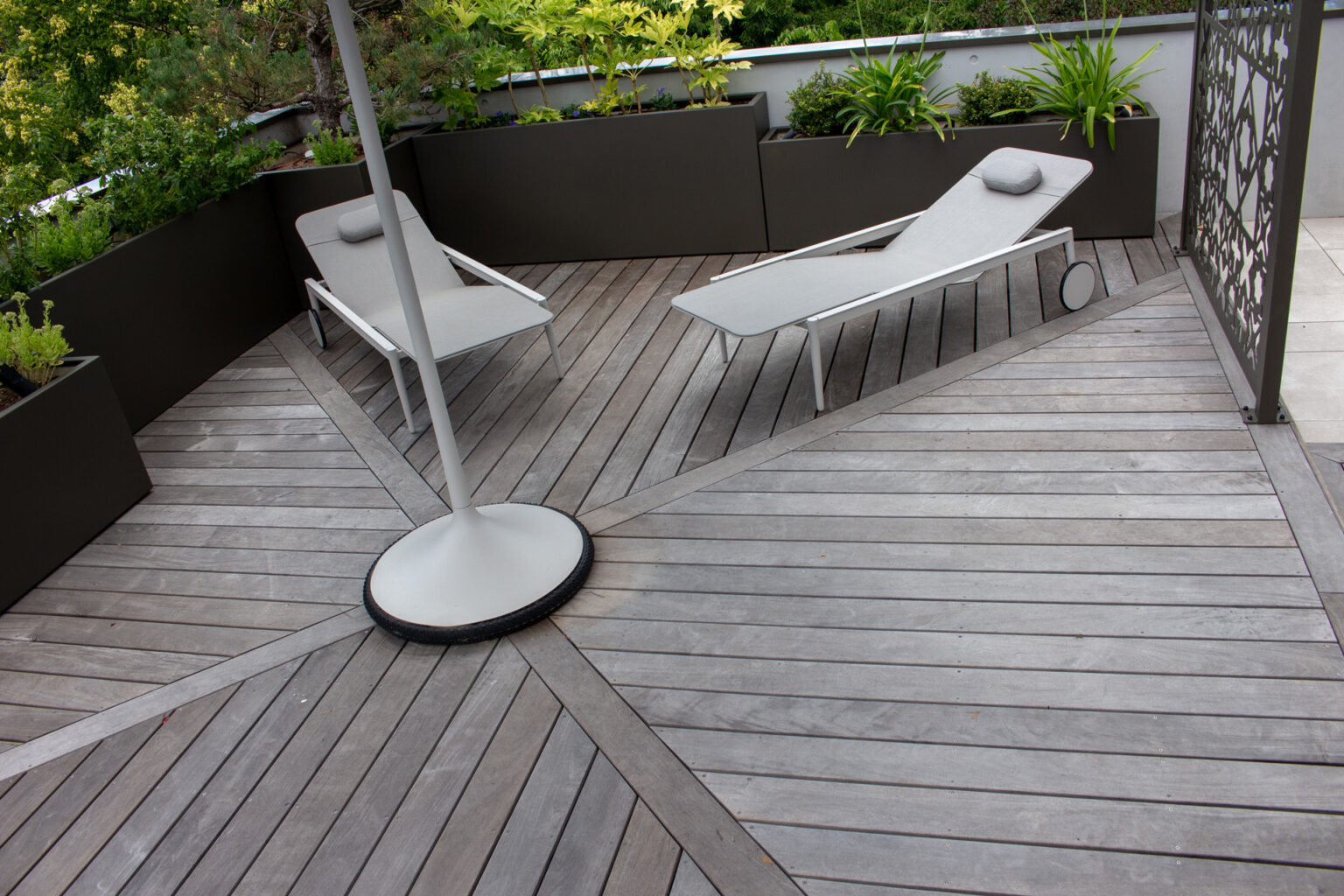 Vue plongeante sur le calepinage en chevrons de la terrasse ipé, bains de soleil et bacs plantés – projet ACER