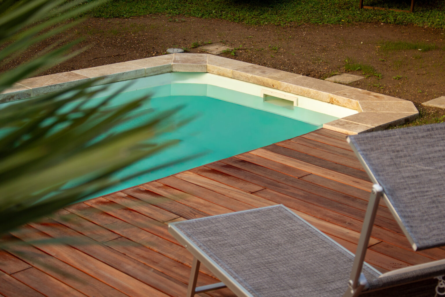 Angle de la piscine avec margelles épaisses en travertin et plage en bois exotique, bain de soleil – projet LAVANDULA