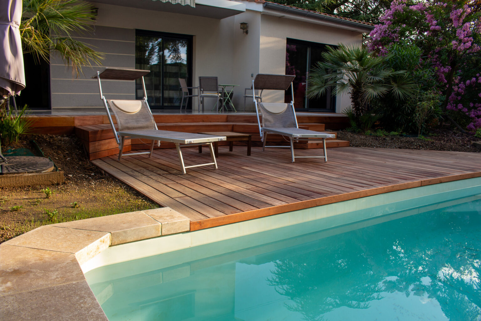 Bains de soleil sur la plage bois au bord de la piscine, maison et lagerstroemia rose en arrière-plan – projet LAVANDULA
