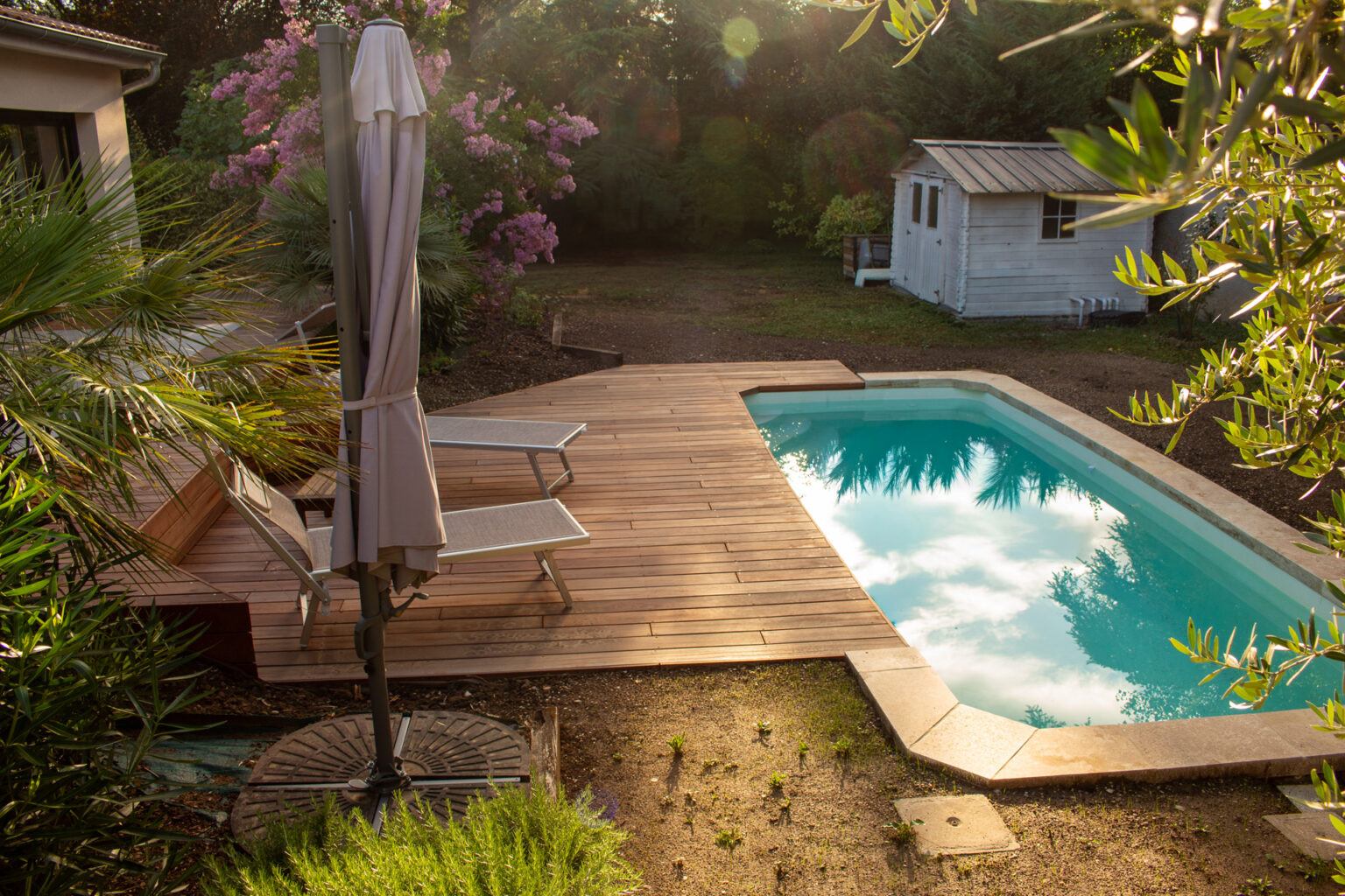 Vue plongeante sur la piscine et sa plage en bois exotique, parasol déporté et lagerstroemia rose – projet LAVANDULA