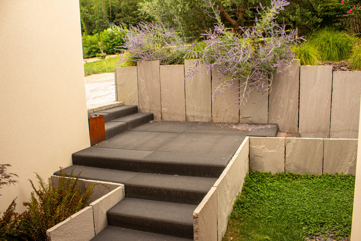 Escalier et palier en dalles de béton anthracite bordés de murets en plaques de grès gris et pelouse – projet LOROPETALUM