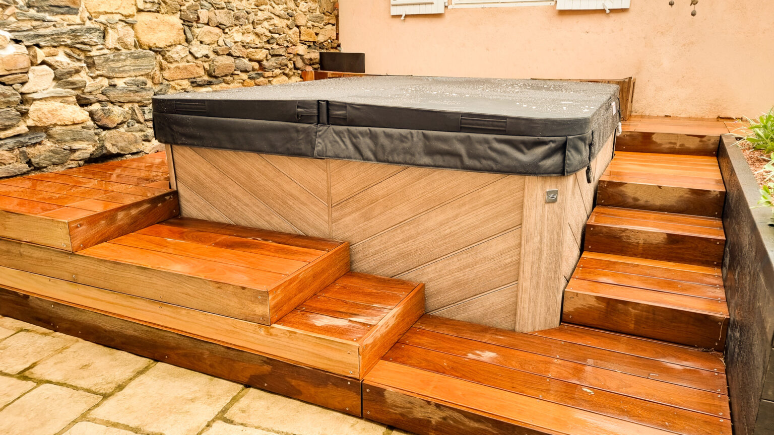 Spa habillé de panneaux bois à chevrons encadré de deux escaliers ipé, jardinière noire à droite – projet SYRINGA