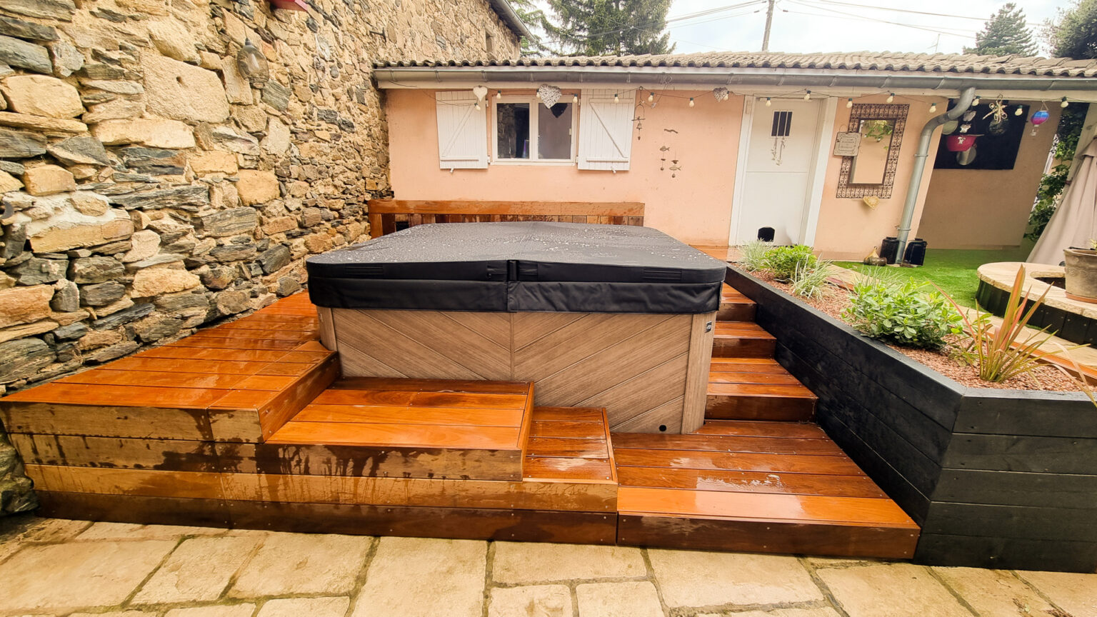 Spa habillé de caissons bois avec plage en platelage ipé sur deux niveaux contre un mur de pierre – projet SYRINGA