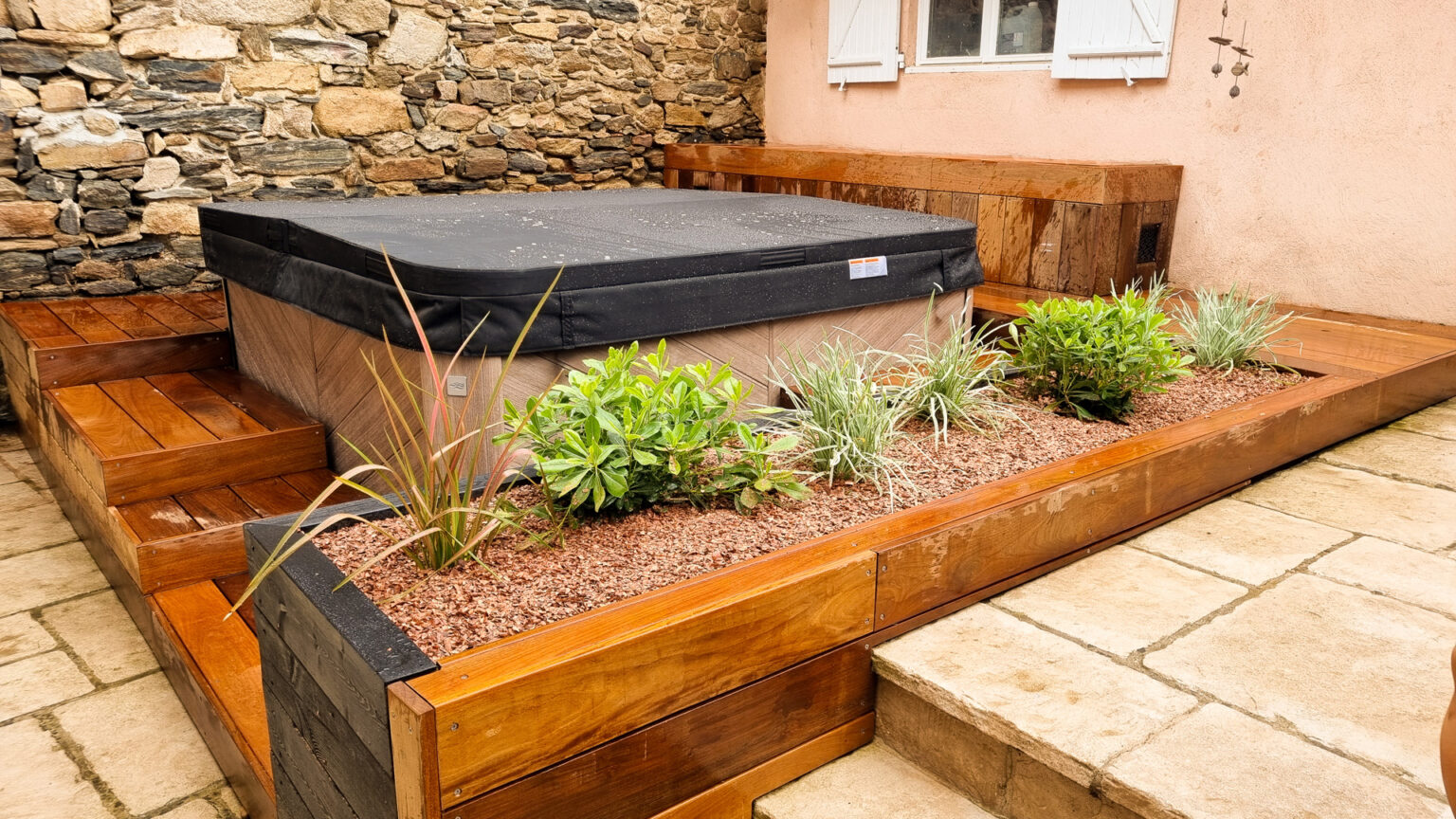Jardinière en pin traité plantée de phormium, pittosporum et fétuques sur paillis au pied du spa habillé – projet SYRINGA