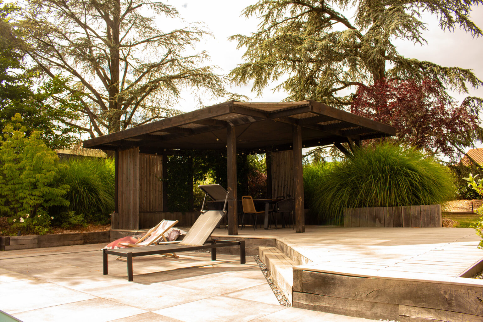 Pergola bois sur mesure abritant l'espace repas, terrasse en platelage bois surélevée, bains de soleil – projet SALVIA
