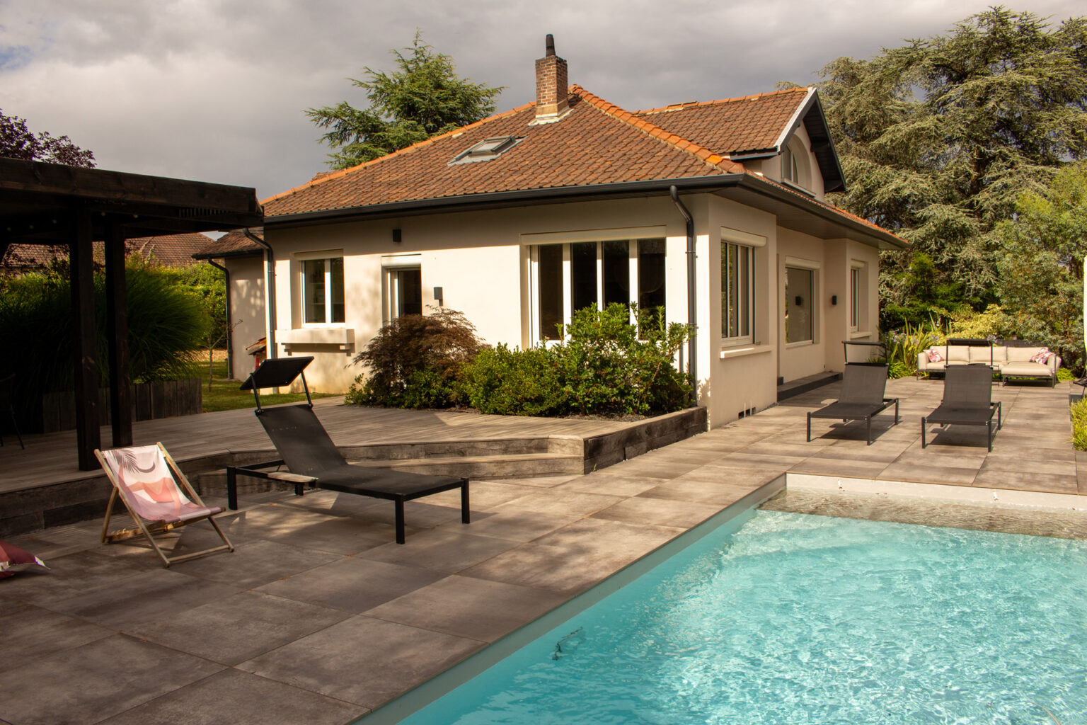 Piscine et terrasse dallée sous la maison, marches en traverses bois, bains de soleil, pergola à gauche – projet SALVIA